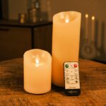 Zestaw 2 ładowalnych świec LED z wosku DORSETTO – wysoka i niska świeca na drewnianym stole z pilotem, nastrojowe rozmyte tło