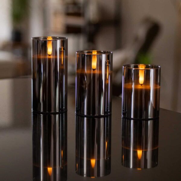 Trzy szklane świeczniki z ładowalnymi świecami LED DORSETTO (105 godzin, płomień 3D, pilot), tworzące ciepłą i luksusową atmosferę na wyjątkowe okazje.