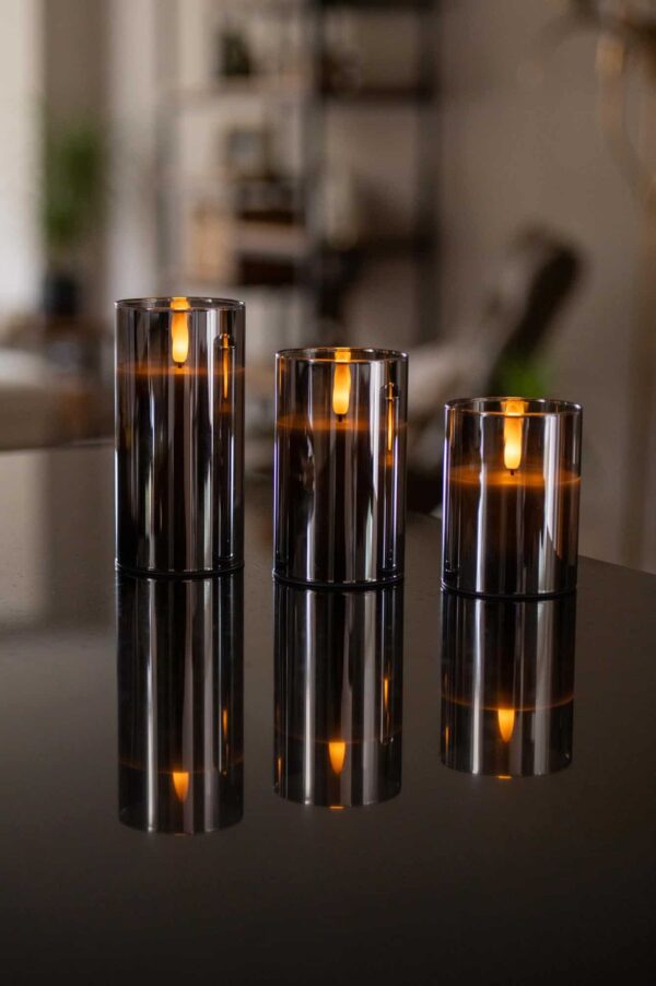 Trzy szklane świeczniki z ładowalnymi świecami LED DORSETTO (105 godzin, płomień 3D, pilot), tworzące ciepłą i luksusową atmosferę na wyjątkowe okazje.