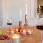 verschillende kaarsen met wijnglazen en borrelplank op een tafel