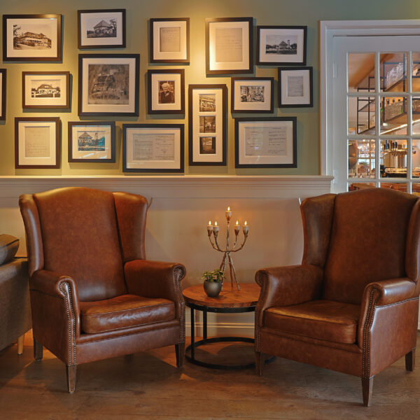 2 rode stoelen met een kandelaar en ingelijste foto's aan de muur