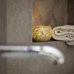 een kaarsje op een muurtje met een handdoek er bij in de badkamer