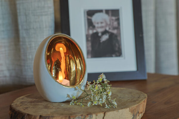 waxinelichtje in houder met takje bij foto van persoon