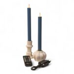 Dwie niebieskie stołowe świece LED w białych świecznikach z czarnym pilotem i zasilaczem, ustawione na białym tle. Świece posiadają realistyczny efekt płomienia.