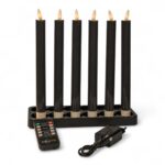 Zestaw sześciu ładowalnych, ciemnoszarych świec obiadowych LED o wysokości 250 mm z funkcją ściemniania i timerem, ustawionych w prostokątnym czarnym świeczniku. W komplecie pilot zdalnego sterowania oraz zasilacz sieciowy z przewodem.