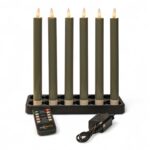 Zestaw sześciu ściemnialnych, ładowalnych świec obiadowych LED o wysokości 250 mm stoi pionowo w prostokątnej podstawie; z przodu umieszczono pilot zdalnego sterowania oraz zasilacz z przewodem, całość na białym tle.