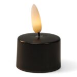 Mały czarny LED tealight z plastikowym płomieniem emitującym ciepłe, żółtawe światło.