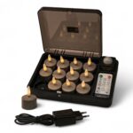 Zestaw 12 ładowalnych podgrzewaczy Charleston Grey (czas świecenia do 400 godzin) z pilotem, skrzynką ładującą, jedną świeczką poza skrzynką oraz czarnym zasilaczem z przodu.